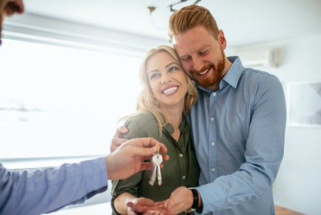 Smiling couple accepting keys to new construction