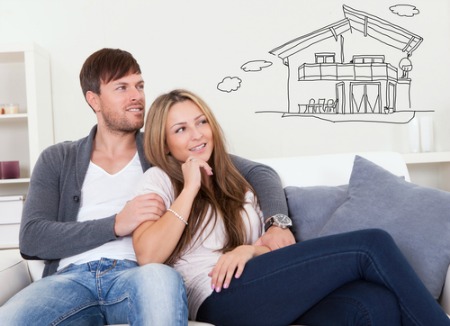 man and woman sitting on sofa and day dreaming about house to buy